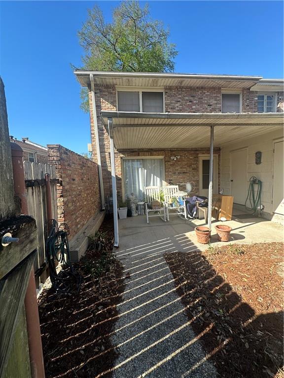 back of property featuring a patio, brick siding, and fence