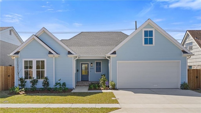 view of front of property with a front yard, fence, an attached garage, a shingled roof, and concrete driveway