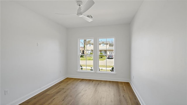 empty room featuring visible vents, a ceiling fan, baseboards, and wood finished floors