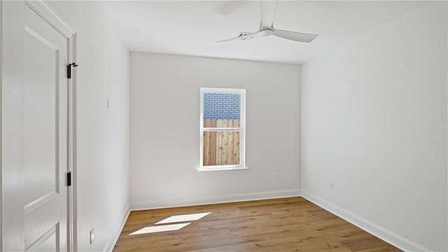 spare room with baseboards, wood finished floors, and a ceiling fan