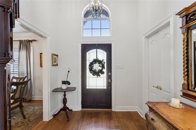 entryway featuring dark wood-style floors, baseboards, and a chandelier