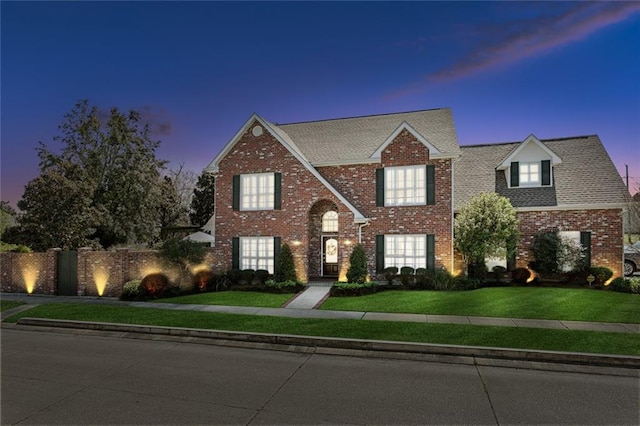 view of front of home featuring a front yard, fence, and brick siding