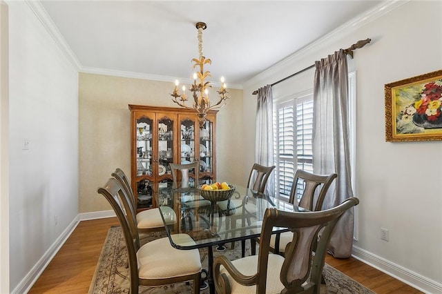 dining space with crown molding, wood finished floors, baseboards, and a chandelier