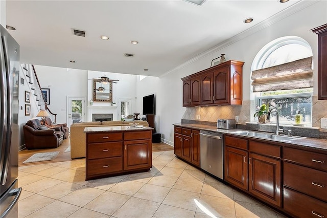 kitchen with visible vents, a fireplace, a sink, decorative backsplash, and appliances with stainless steel finishes