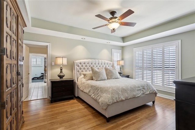 bedroom featuring baseboards, multiple windows, and light wood-style flooring