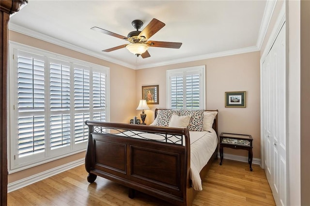 bedroom featuring ornamental molding, a closet, light wood finished floors, baseboards, and ceiling fan