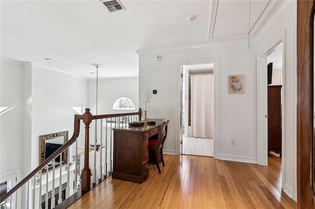 hallway featuring visible vents, crown molding, attic access, light wood-type flooring, and an upstairs landing