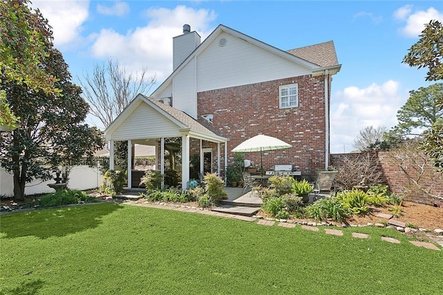 back of house with a lawn, fence, a sunroom, brick siding, and a chimney