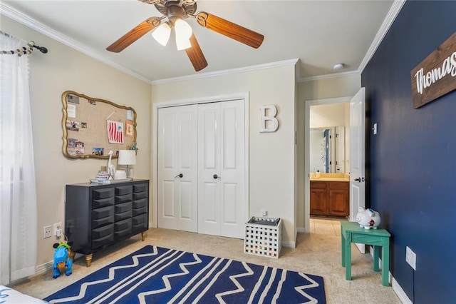 carpeted bedroom with a closet, baseboards, crown molding, and ceiling fan