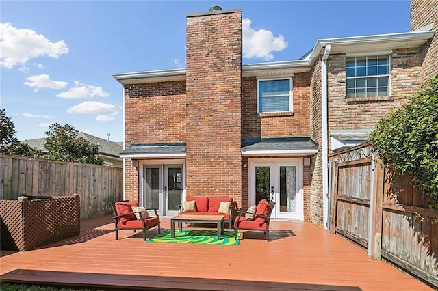 back of house featuring french doors, brick siding, a deck, and fence