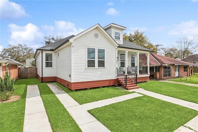 bungalow-style house featuring a porch, roof with shingles, a front lawn, and fence