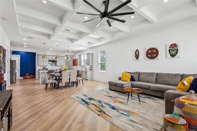 living room featuring beam ceiling, light wood-style flooring, a ceiling fan, coffered ceiling, and recessed lighting