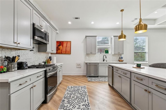 kitchen featuring light wood-type flooring, visible vents, gray cabinets, and stainless steel appliances