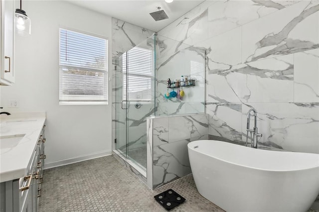 bathroom featuring a marble finish shower, a freestanding bath, double vanity, tile walls, and a sink