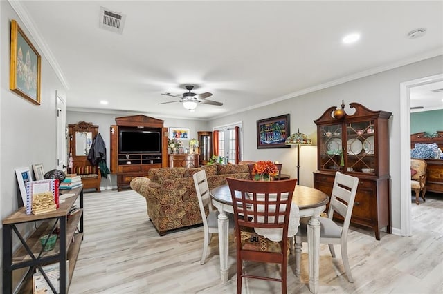 dining room featuring visible vents, light wood-type flooring, crown molding, and a ceiling fan