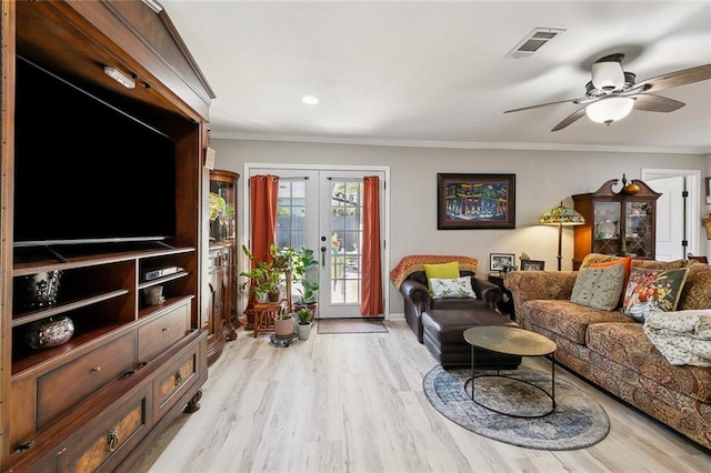 living room featuring light wood-type flooring, visible vents, ornamental molding, a ceiling fan, and french doors