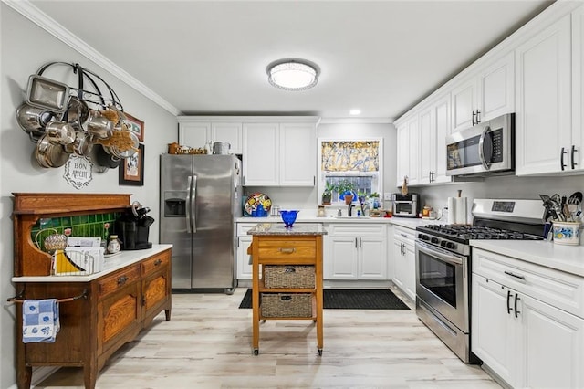 kitchen with light wood finished floors, white cabinets, appliances with stainless steel finishes, and ornamental molding