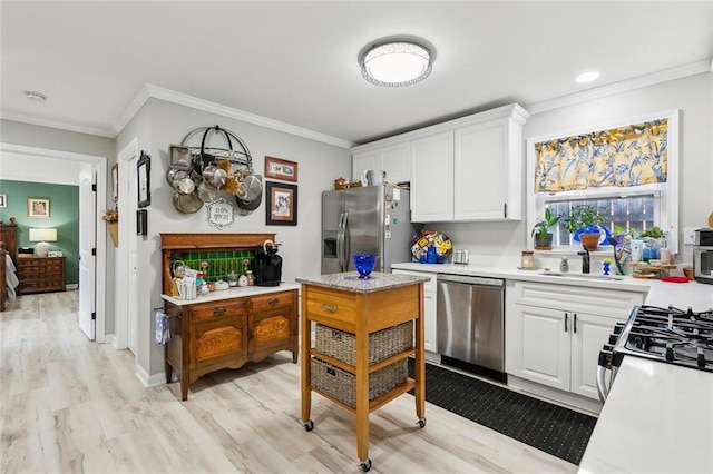 kitchen with light countertops, white cabinets, ornamental molding, and stainless steel appliances