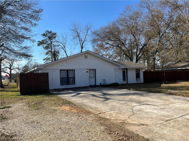 back of house featuring brick siding, driveway, and fence