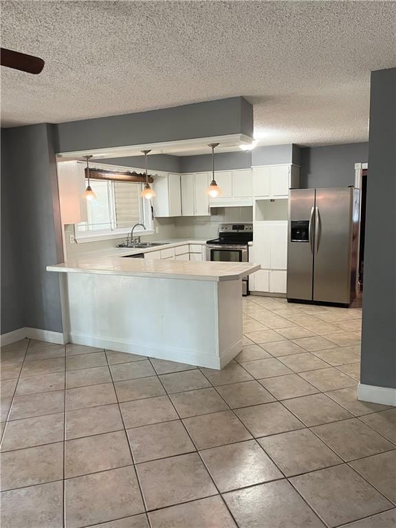 kitchen with light tile patterned floors, a peninsula, stainless steel appliances, light countertops, and white cabinets