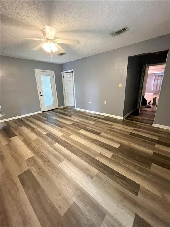 unfurnished room featuring visible vents, baseboards, a textured ceiling, and wood finished floors