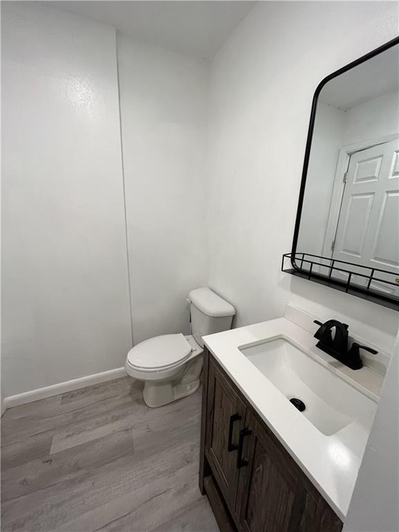 bathroom featuring toilet, vanity, baseboards, and wood finished floors