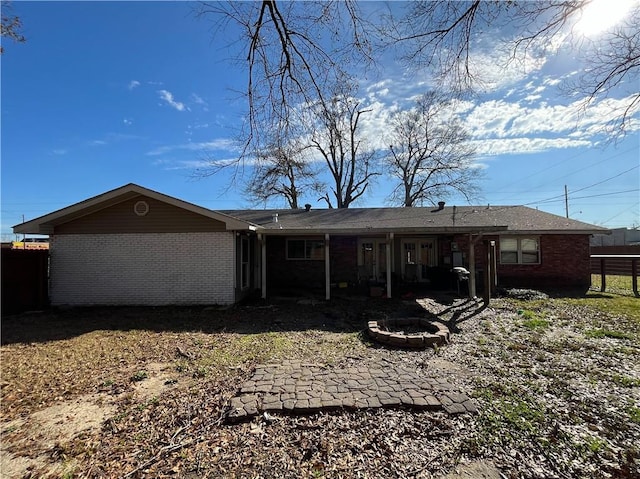 rear view of property with fence, brick siding, and an outdoor fire pit