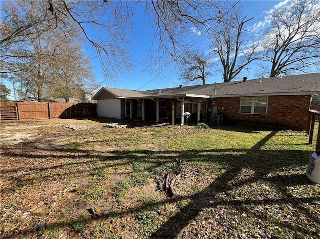 back of property with brick siding, cooling unit, a yard, and fence