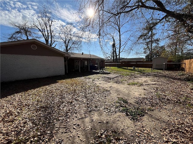 view of yard with a storage shed, an outdoor structure, and fence