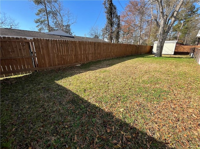 view of yard featuring a storage unit, an outdoor structure, and a fenced backyard