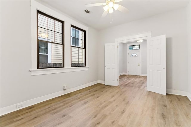 empty room featuring light wood-type flooring, visible vents, baseboards, and ceiling fan