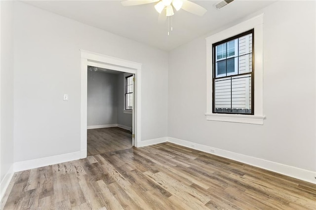 spare room with visible vents, a ceiling fan, baseboards, and wood finished floors