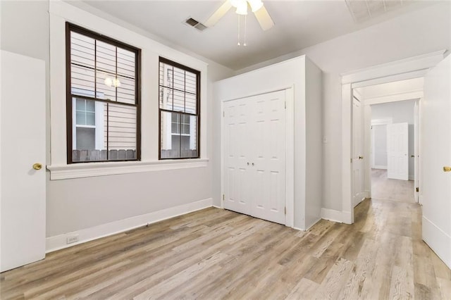 unfurnished bedroom with wood finished floors, visible vents, baseboards, ceiling fan, and a closet