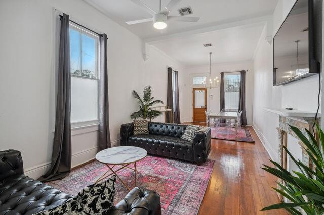 living area with visible vents, baseboards, a healthy amount of sunlight, and hardwood / wood-style floors