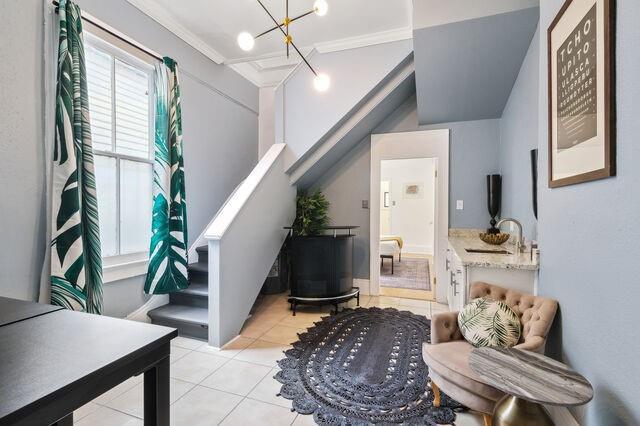 interior space featuring an inviting chandelier, light tile patterned flooring, stairs, and ornamental molding