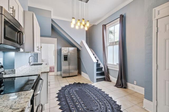 kitchen with light tile patterned floors, a notable chandelier, stainless steel appliances, and ornamental molding