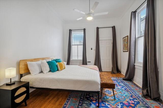 bedroom featuring wood finished floors, ceiling fan, and ornamental molding