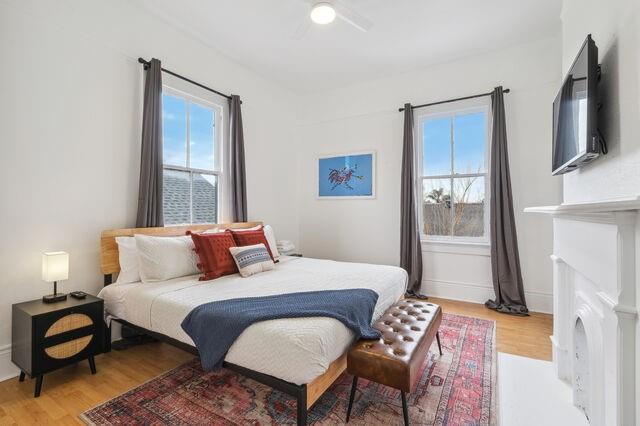 bedroom featuring light wood-style flooring, multiple windows, and ceiling fan