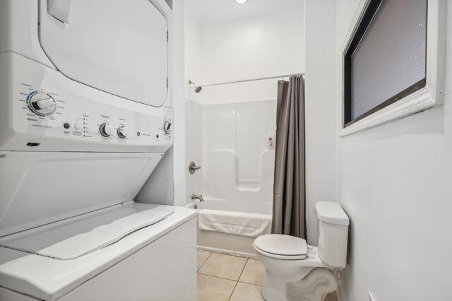 bathroom with tile patterned floors, toilet, shower / bathtub combination, and stacked washing maching and dryer