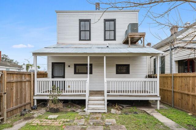 view of front of house with a porch, metal roof, and fence