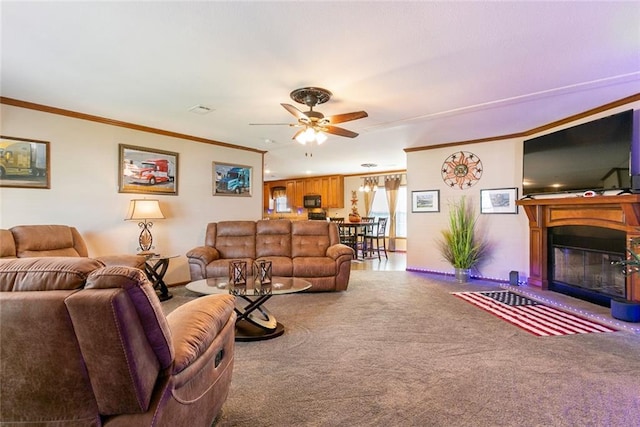 carpeted living area featuring a glass covered fireplace, a ceiling fan, and ornamental molding