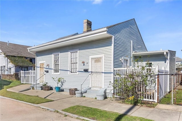 view of front of house featuring entry steps, fence, and a chimney