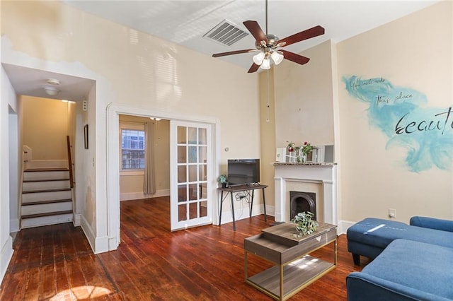 living room with wood finished floors, baseboards, visible vents, a fireplace, and stairs