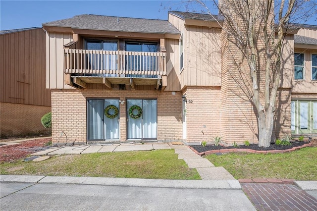 view of front facade featuring brick siding and a balcony