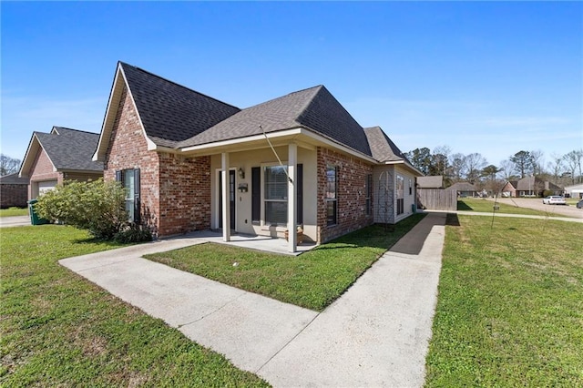 view of front of house with a front yard, brick siding, and a shingled roof