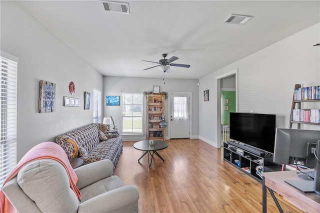 living area with baseboards, wood finished floors, visible vents, and ceiling fan