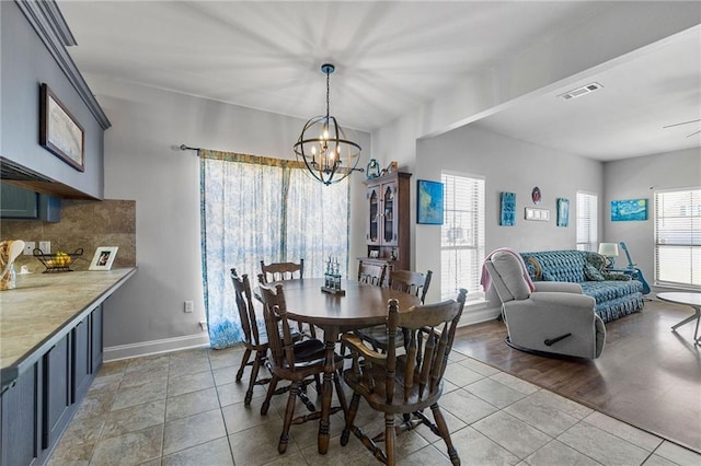 dining space featuring light tile patterned floors, visible vents, baseboards, and an inviting chandelier