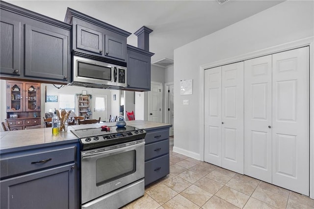 kitchen with light countertops, light tile patterned floors, baseboards, and appliances with stainless steel finishes