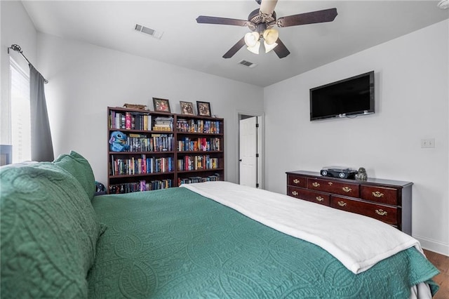 bedroom with visible vents, baseboards, wood finished floors, and a ceiling fan