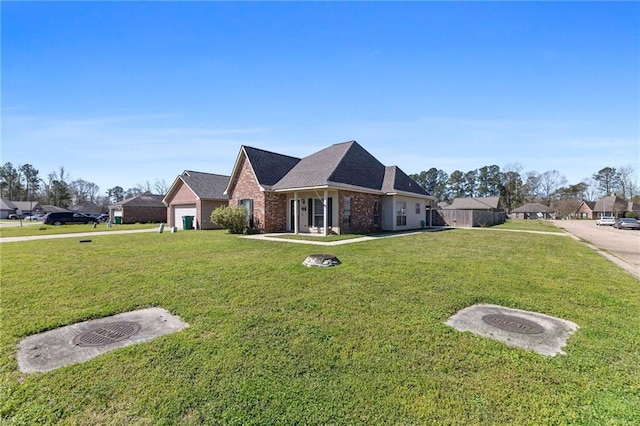 view of front facade featuring a front yard, an attached garage, and brick siding